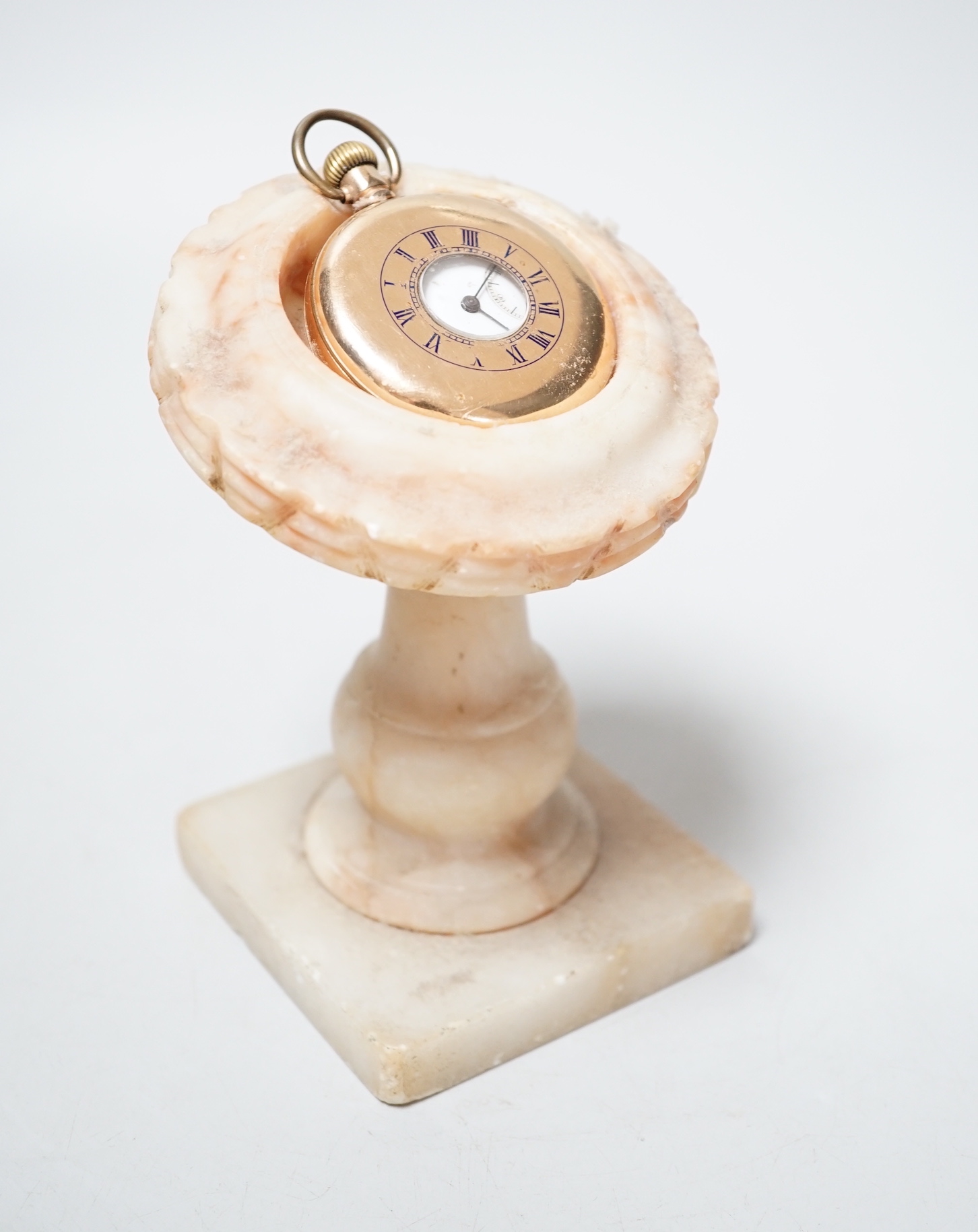 A gold plated pocket watch and carved alabaster stand, total height 14 cm